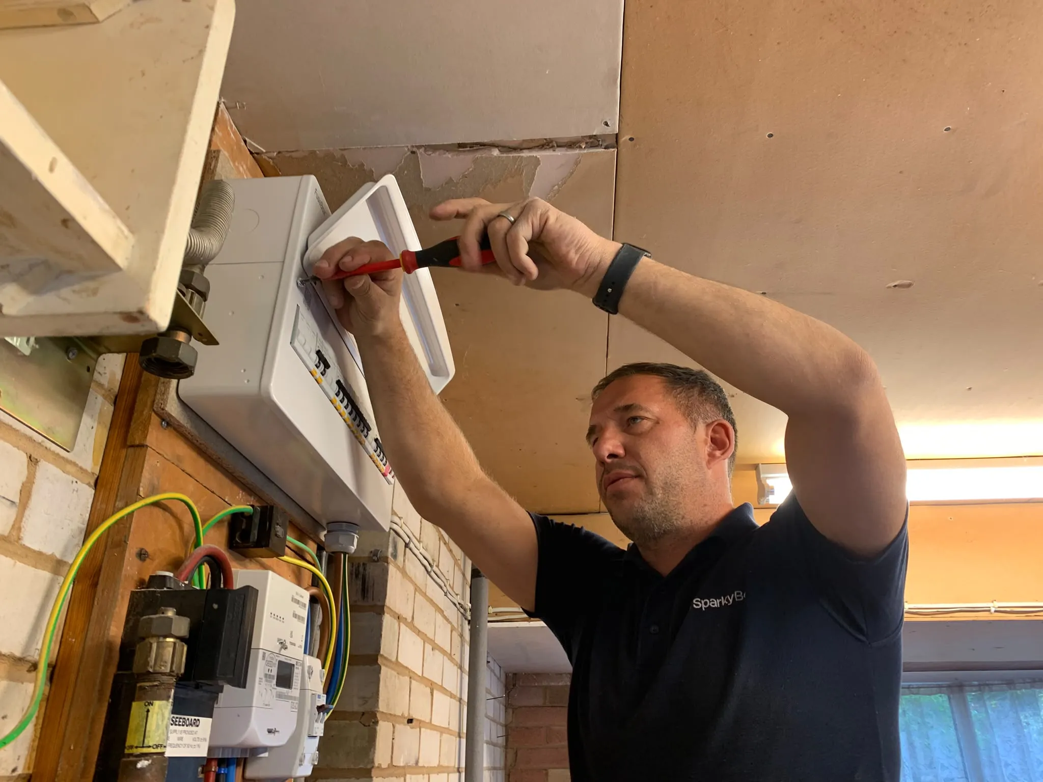 Ben working at a wall-mounted consumer unit